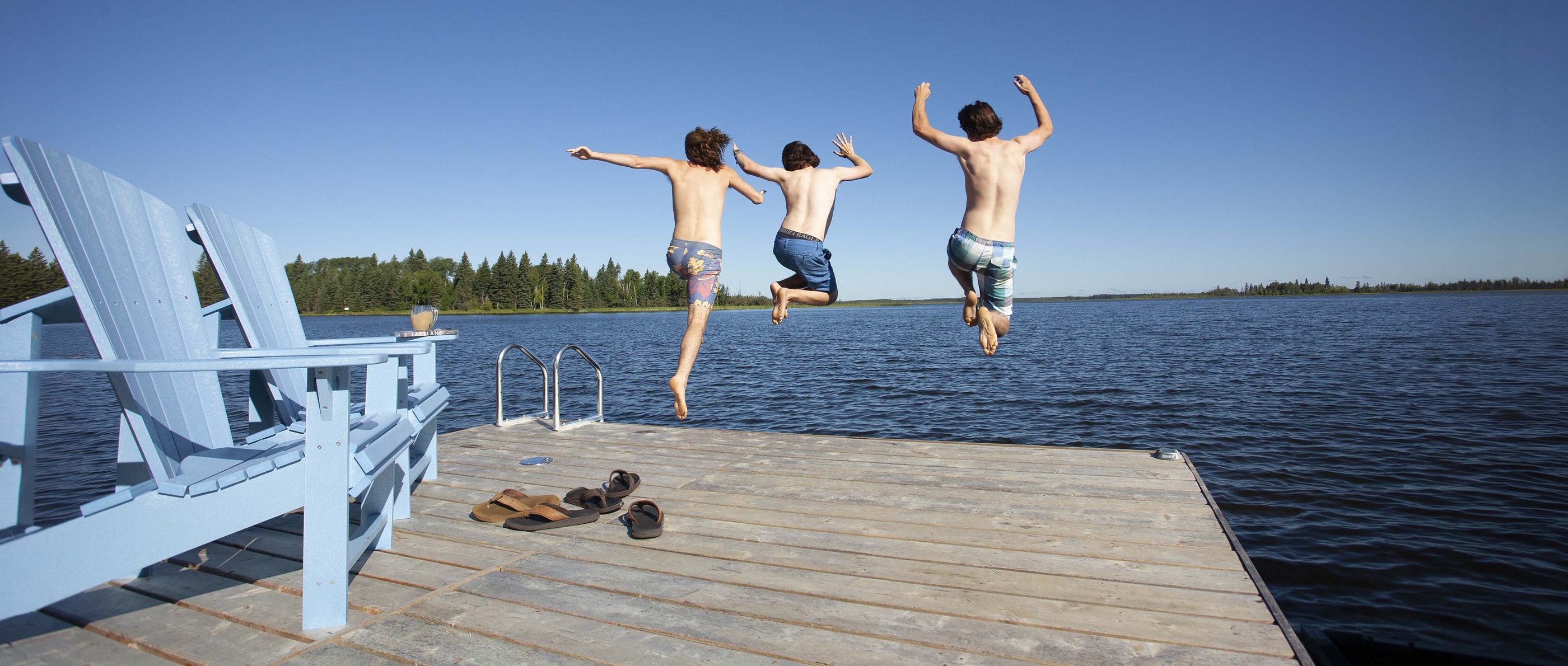 Three boys jumping off a dock into a lake — photography by Karee Davidson